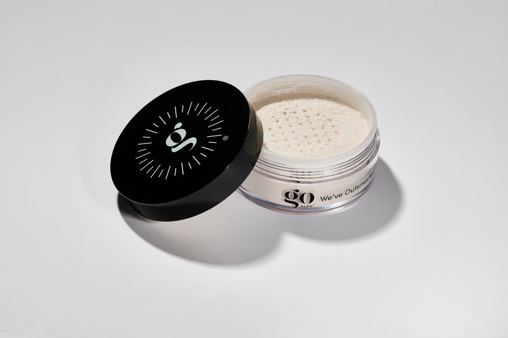 Open container of white powder with black lid on a light gray background